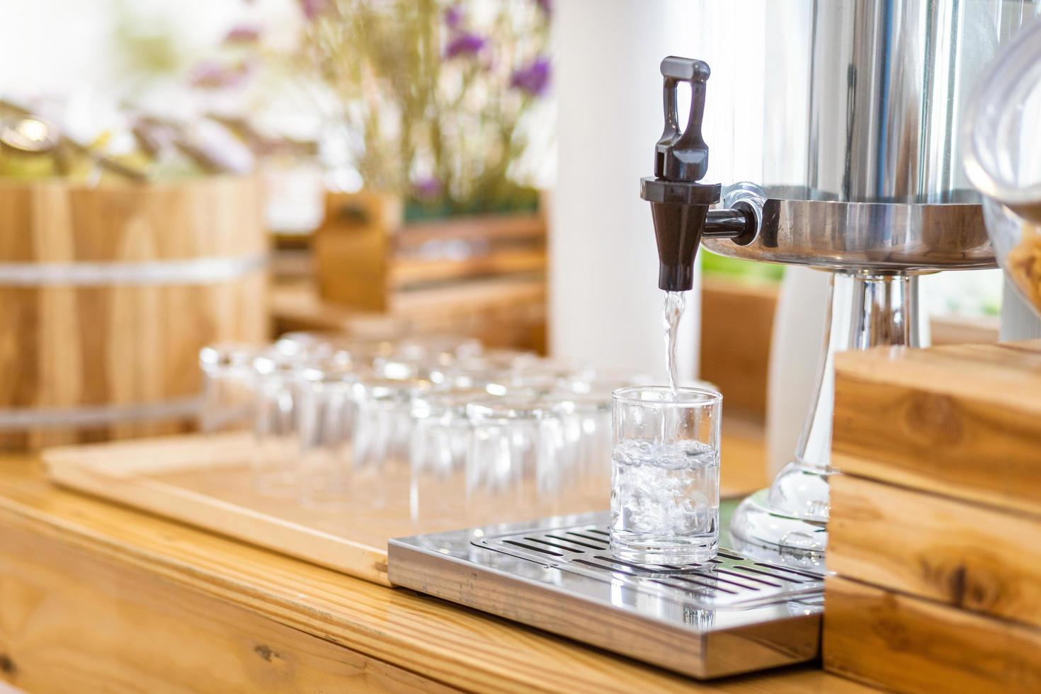 robinet de récipient en verre pour l'eau fraîche au buffet en libre-service à l'hôtel. photo