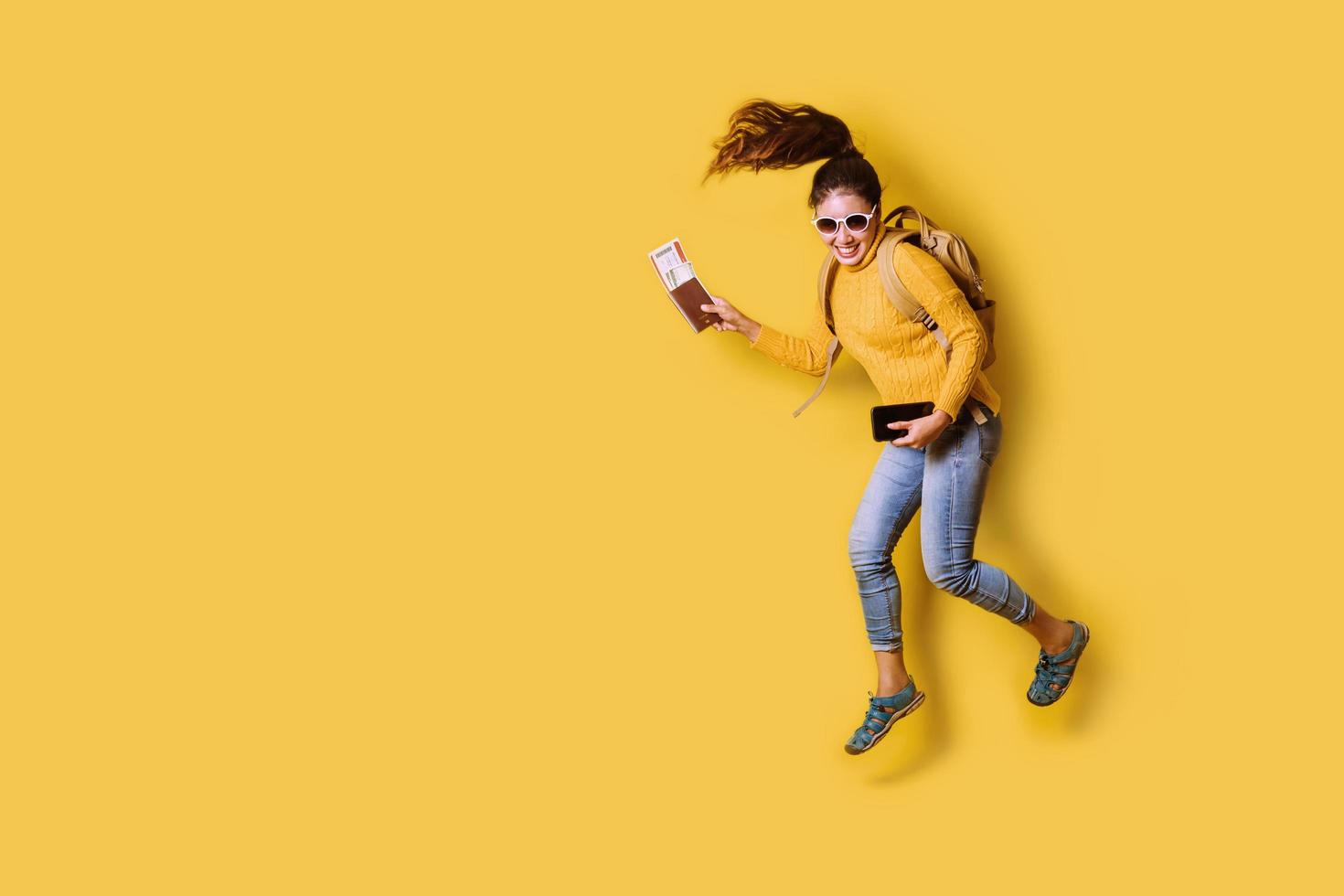 voyageuse avec valise, tenant un passeport avec billet sur fond jaune. portrait de fille heureuse souriante dans la robe jaune. voyageur photo