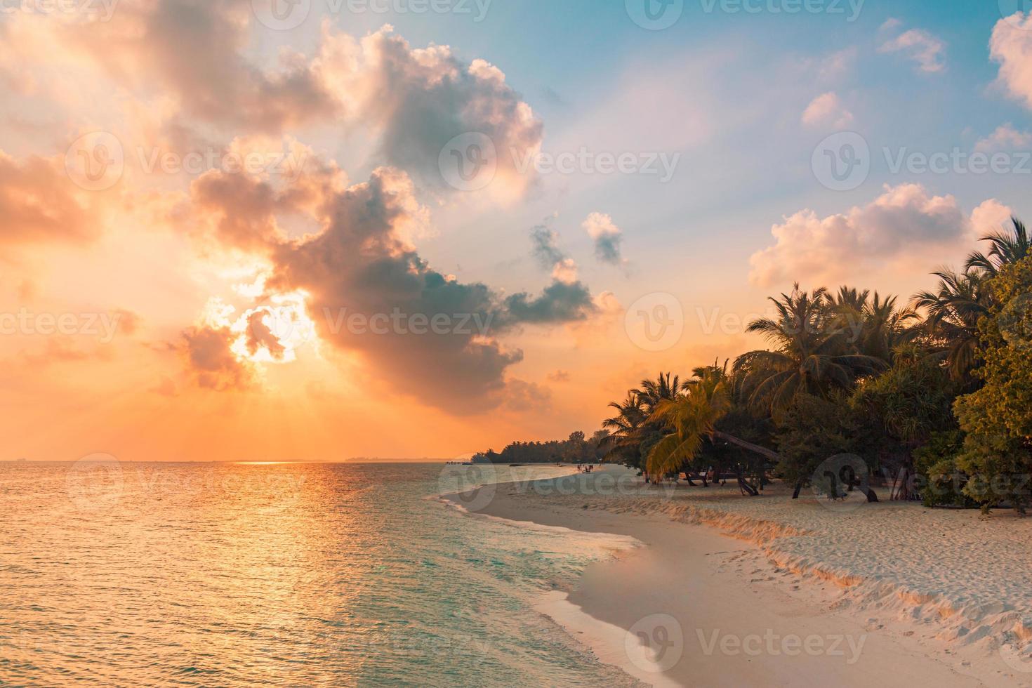 fantastique scène de plage au coucher du soleil. vue colorée sur le ciel et les nuages avec une mer calme et une ambiance tropicale relaxante. rayons de soleil, paysage d'île paradisiaque romantique, silhouette de palmier, soirée de plage incroyable photo