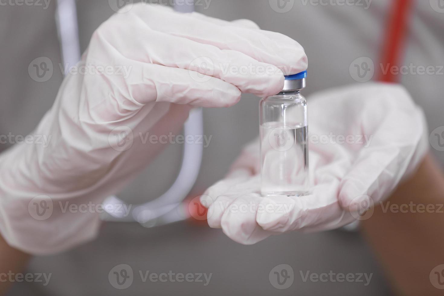 femme médecin avec un stéthoscope sur l'épaule tenant le vaccin covid-19. concept de soins de santé et médical. développement et création d'un vaccin contre le coronavirus. photo