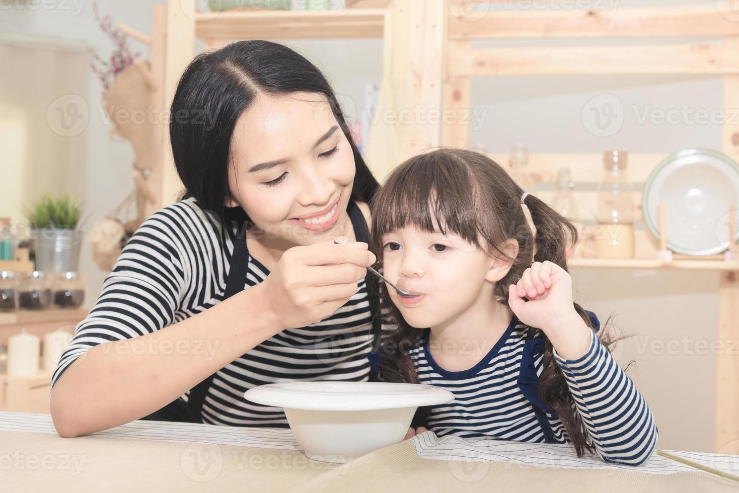 famille heureuse de maman asiatique nourrissant un petit-déjeuner sain à sa jolie fille le matin. série de photos de concept de famille, d'enfants et de gens heureux.