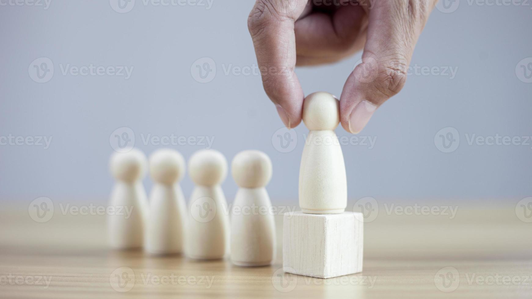 Les mains d'homme d'affaires en gros plan choisissent les meilleures personnes qui réussissent la direction de l'équipe du modèle en bois photo