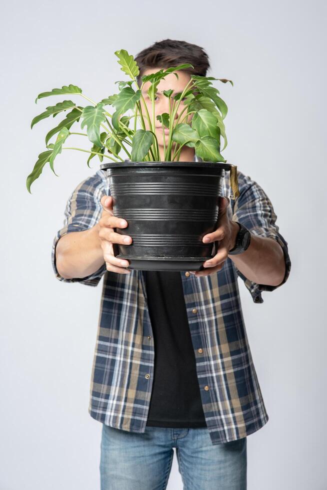 un homme s'est levé et a tenu un pot de plante dans sa maison. photo