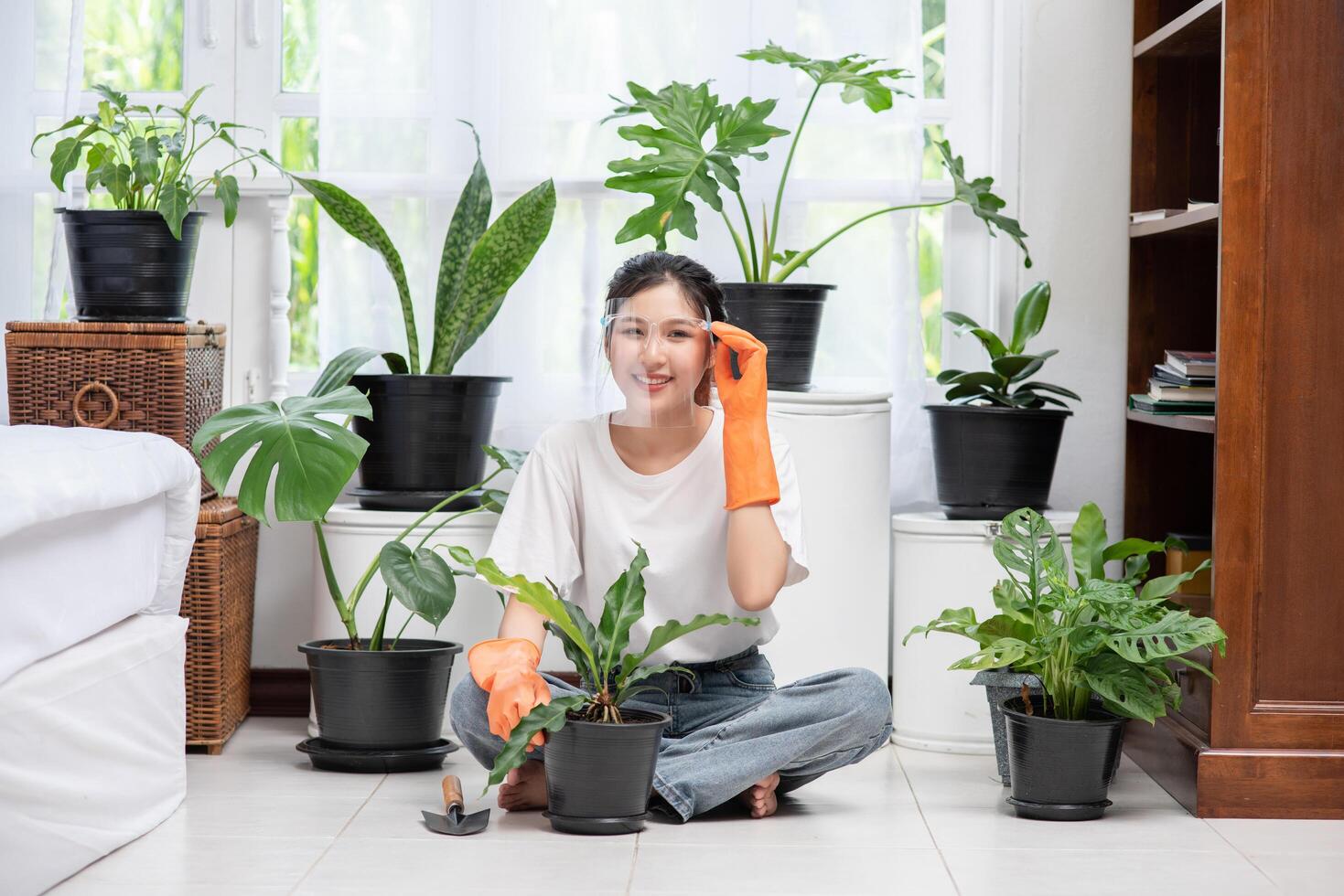 la femme portait des gants orange et a planté des arbres dans la maison. photo