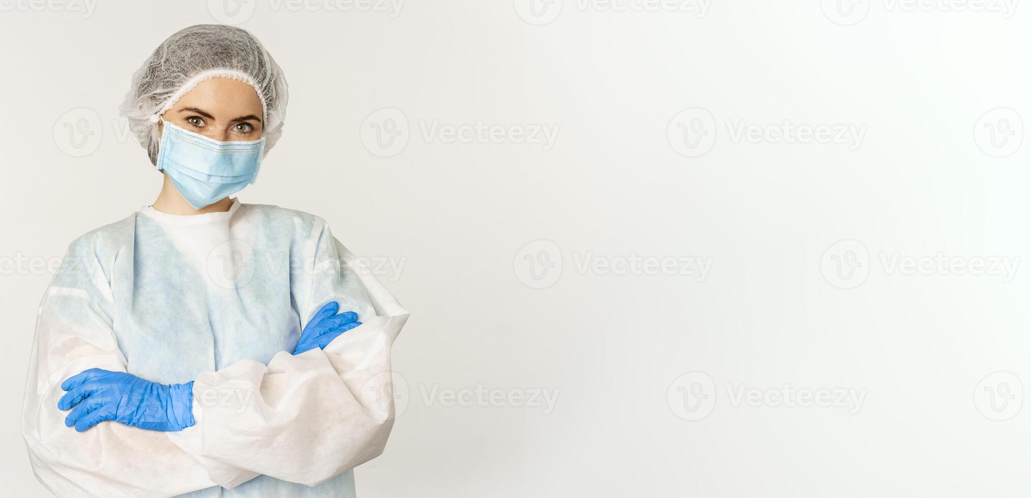 portrait de médecin, femelle infirmière dans personnel protecteur équipement, à la recherche sur de soi et professionnel, permanent plus de blanc Contexte photo