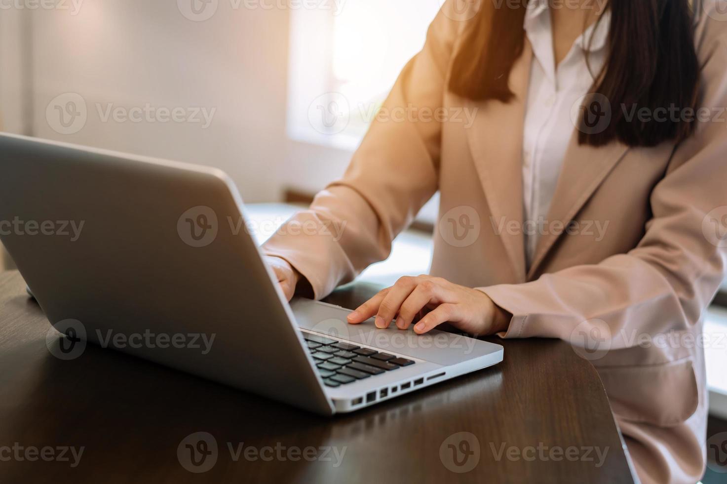 femme d'affaires confiante travaillant sur ordinateur portable et tablette sur son lieu de travail dans un bureau moderne. photo