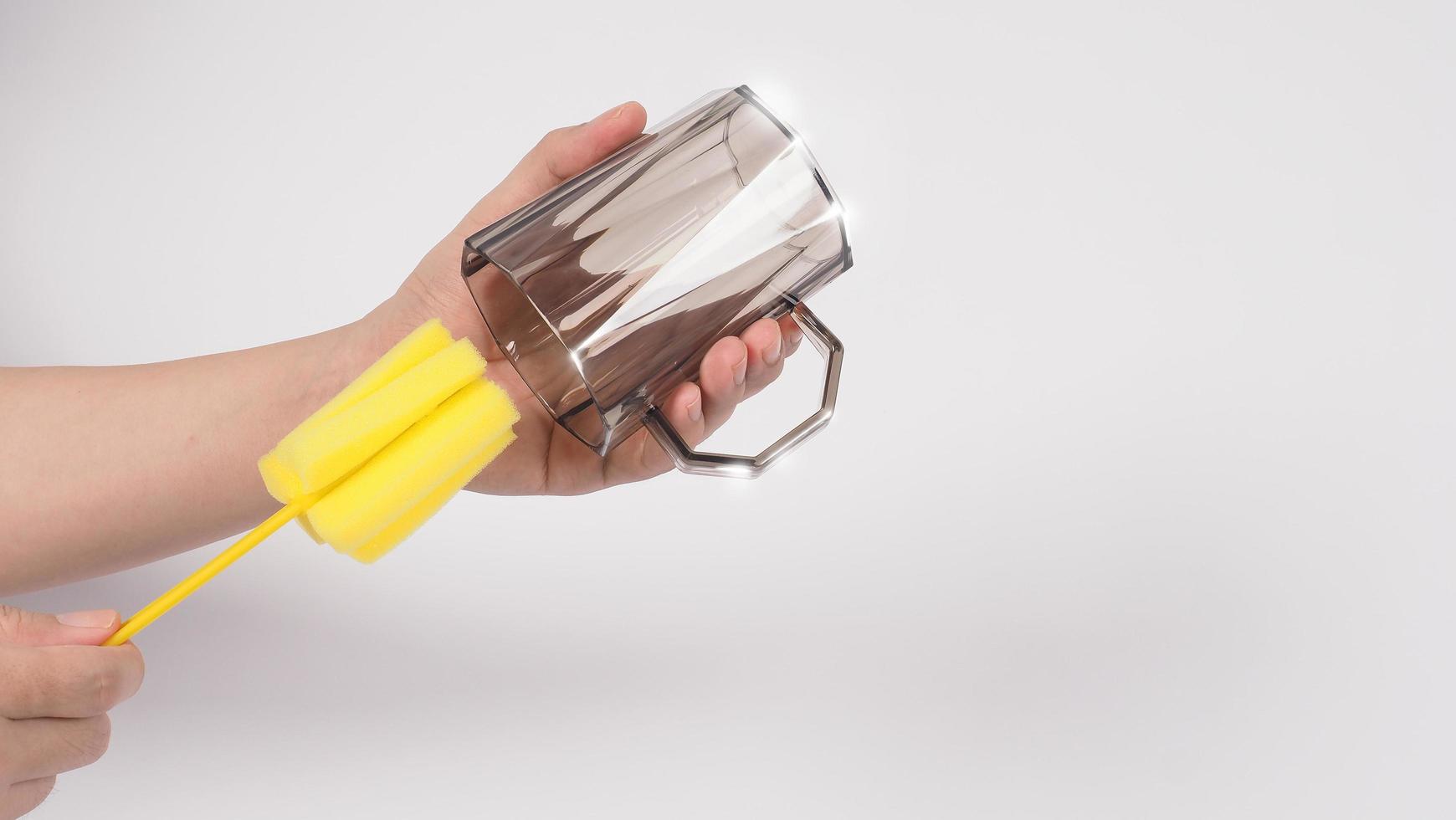 concept de vaisselle propre et lavé. verre de boisson de lavage de main d'homme sur le fond blanc. photo