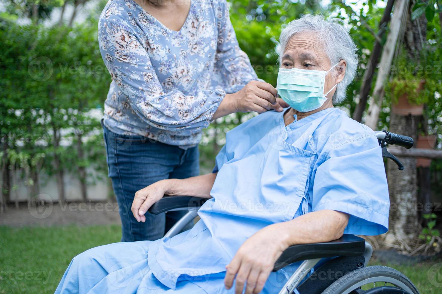 aidez une vieille dame asiatique âgée ou âgée en fauteuil roulant et portant un masque facial pour protéger l'infection de sécurité covid-19 coronavirus dans le parc. photo