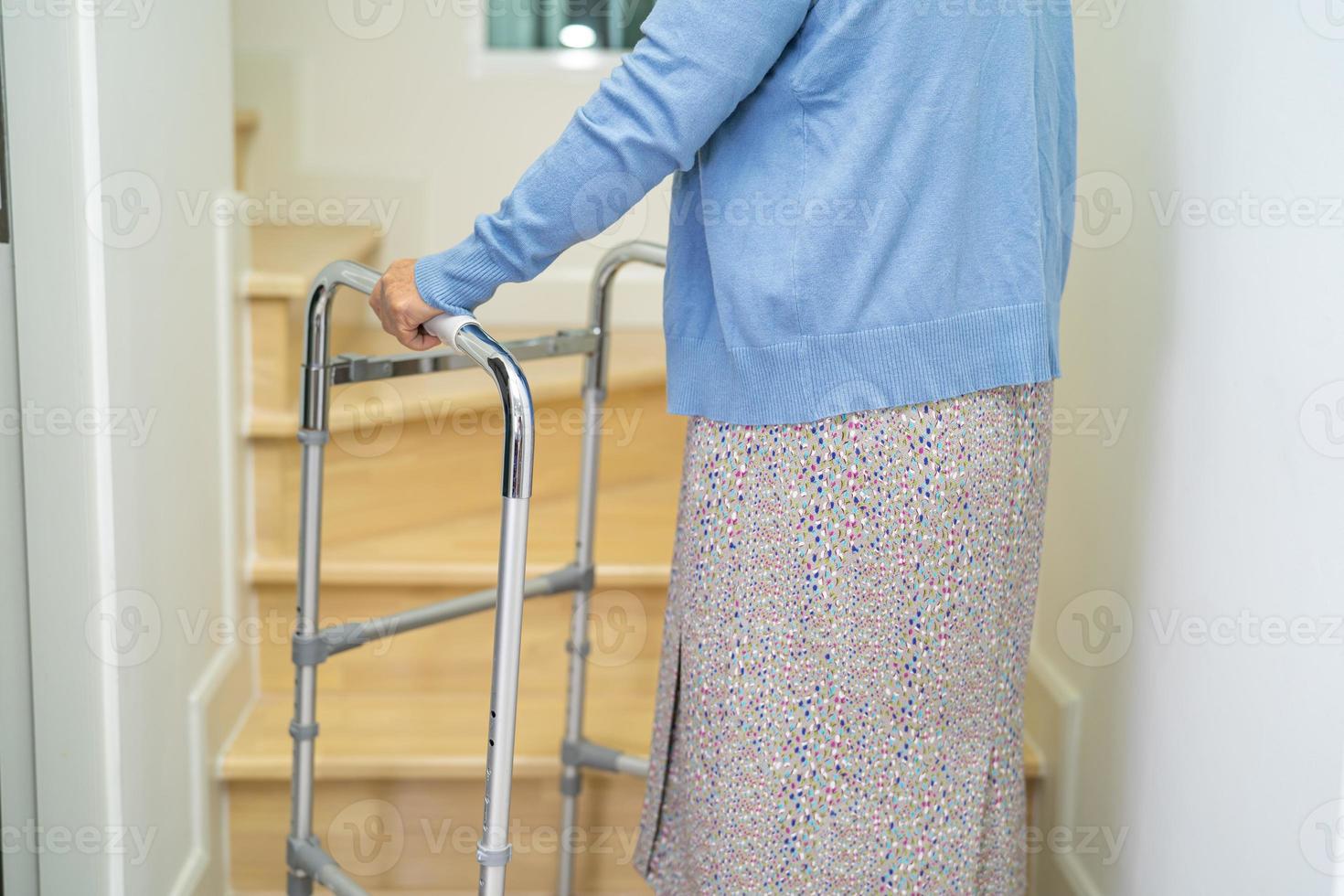 vieille femme asiatique ou âgée marchant avec un support de marcheur dans les escaliers à la maison. photo