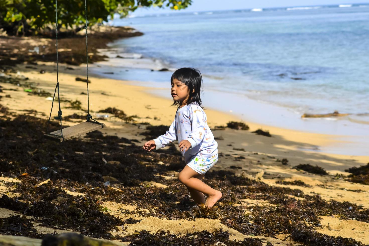 Une petite fille jouant sur une balançoire au bord de la plage photo