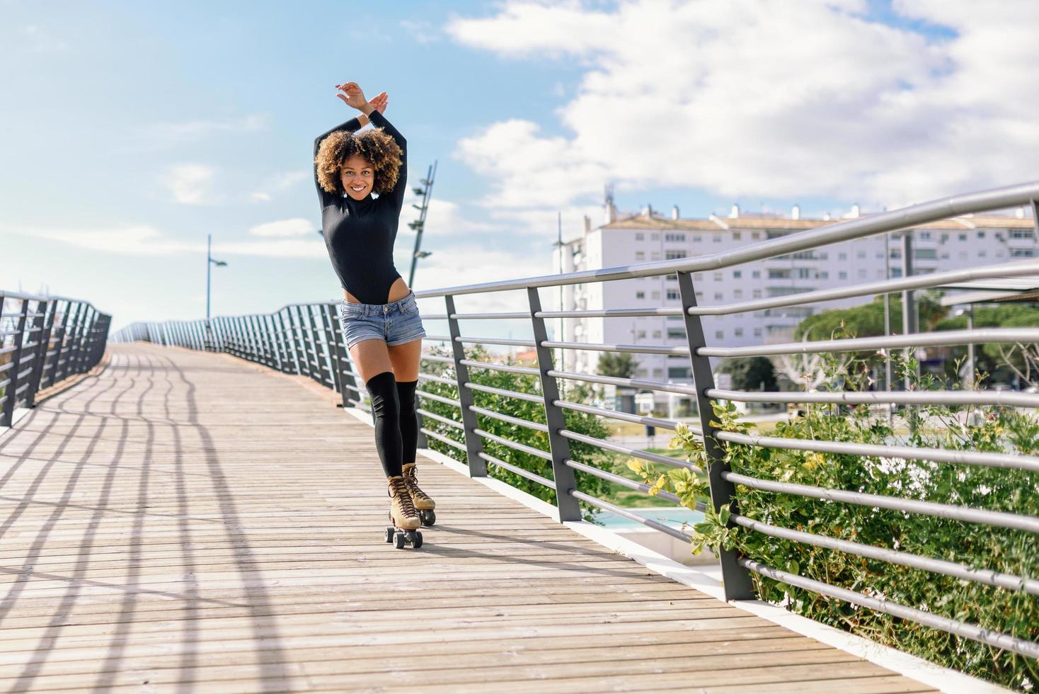 coiffure afro femme sur patins à roulettes à l'extérieur sur le pont urbain photo