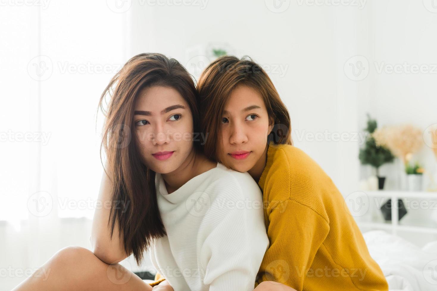 belles jeunes femmes asiatiques lgbt couple heureux lesbien assis sur le lit étreignant et souriant ensemble dans la chambre à la maison. couple de lesbiennes lgbt ensemble concept à l'intérieur. passer du bon temps à la maison. photo