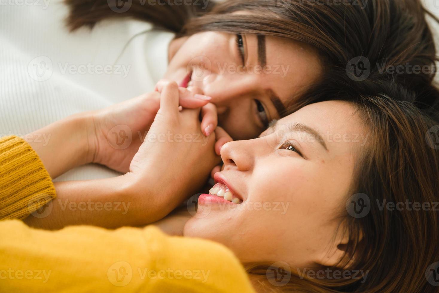 belles jeunes femmes asiatiques lgbt couple heureux lesbien étreignant et souriant en position couchée ensemble dans son lit sous une couverture à la maison. femmes drôles après le réveil. couple de lesbiennes lgbt ensemble concept à l'intérieur. photo