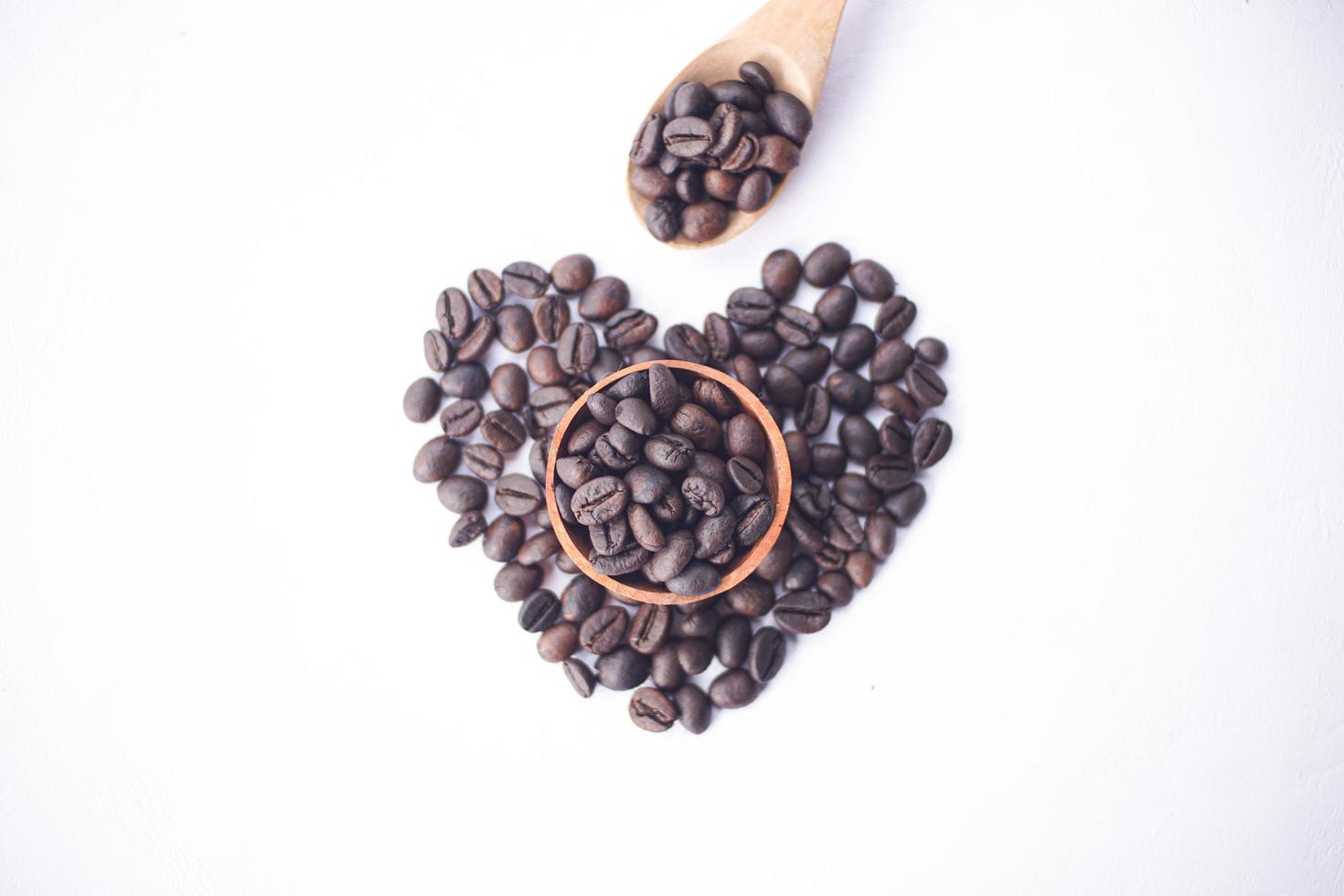 grains de café sur un bol en bois avec forme d'amour photo