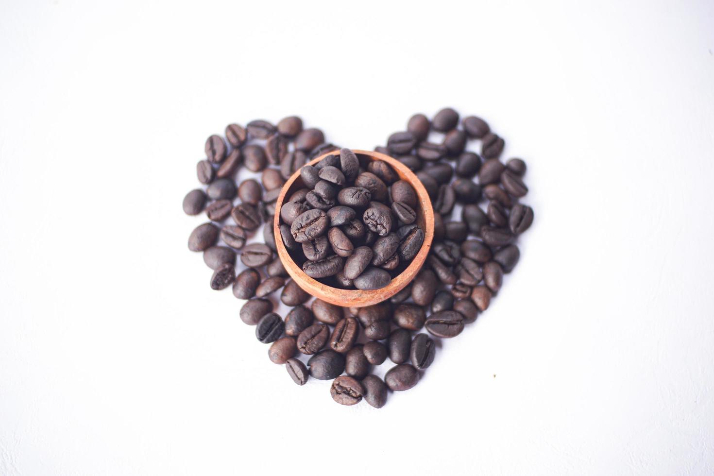 grains de café sur un bol en bois avec forme d'amour photo