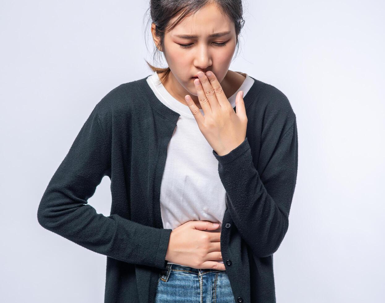 une femme qui a mal au ventre met ses mains sur son ventre et se couvre la bouche. photo