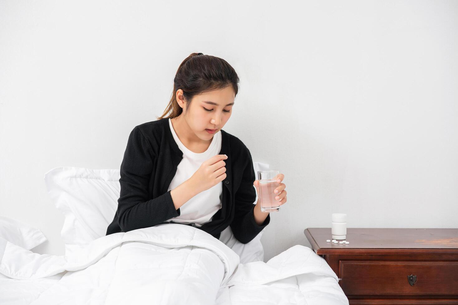 une femme qui ne se sent pas bien sur le canapé et qui s'apprête à prendre des antibiotiques. photo