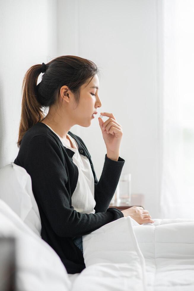 une femme qui ne se sent pas bien sur le canapé et qui s'apprête à prendre des antibiotiques. photo