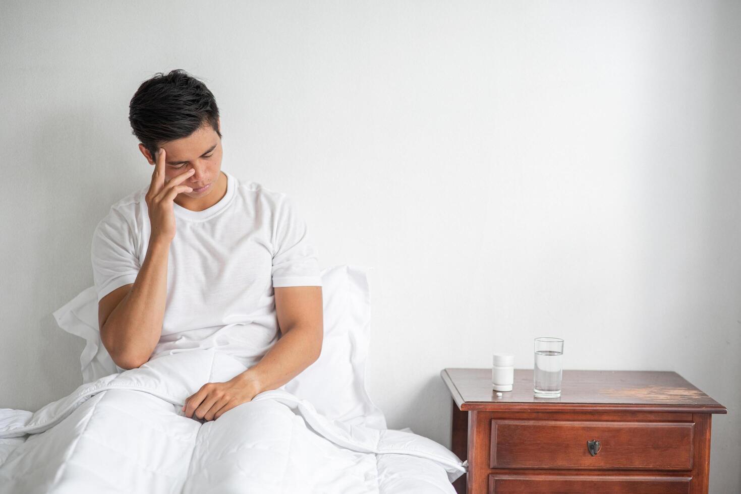 le malade s'assit sur le lit, lui touchant la tête de la main. photo