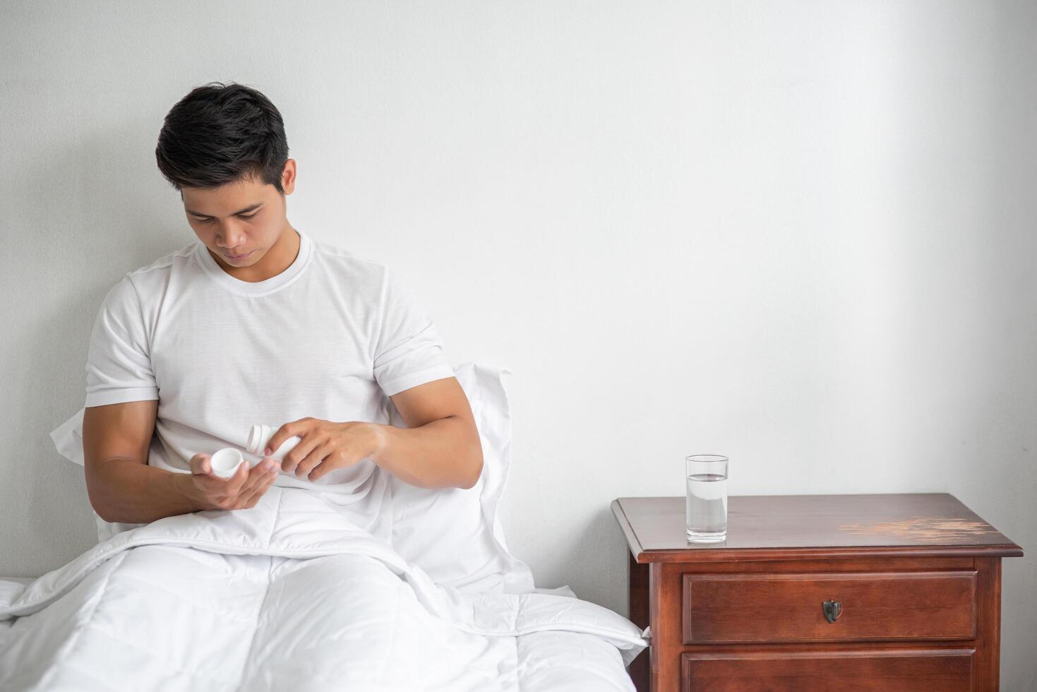 un homme qui ne se sent pas bien sur le canapé et qui s'apprête à prendre des antibiotiques. photo