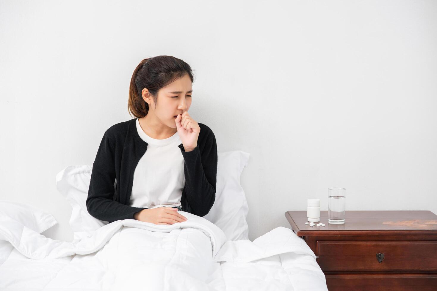 la femme toussa et se couvrit la bouche de sa main et s'assit sur le lit. photo