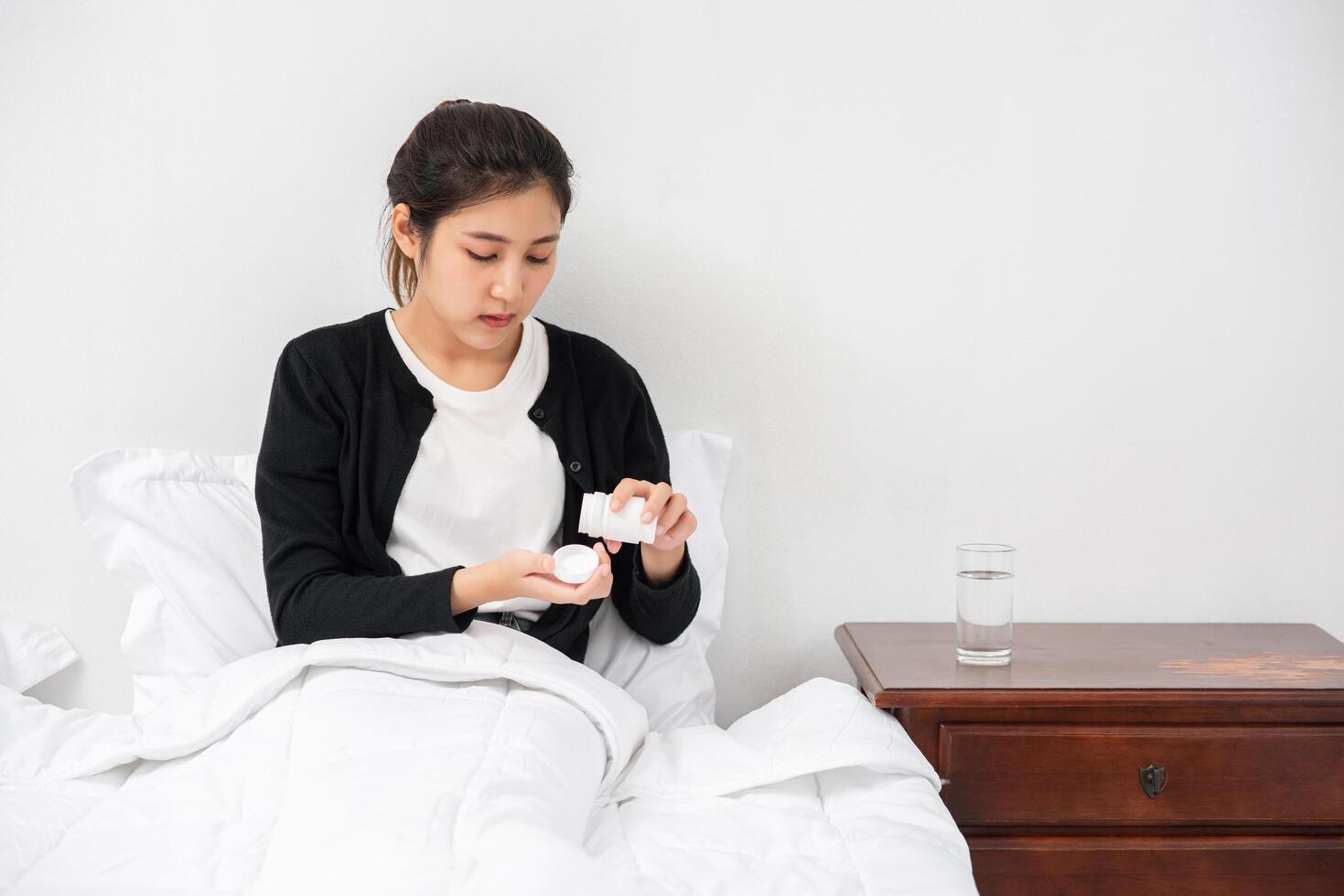 une femme qui ne se sent pas bien sur le canapé et qui s'apprête à prendre des antibiotiques. photo