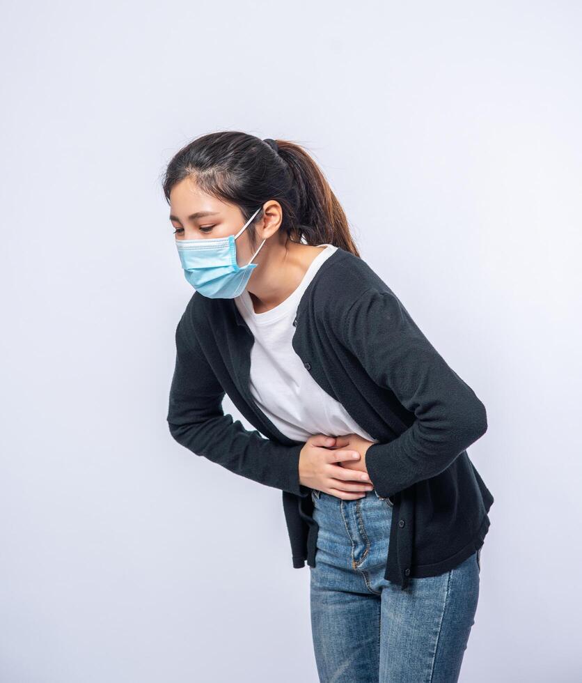 une femme debout avec un mal de ventre et appuie sa main sur son ventre. photo