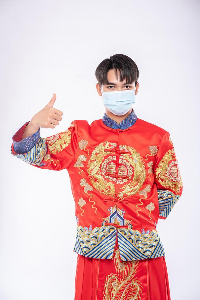 l'homme porte un costume et un masque de cheongsam montrent la meilleure façon de faire des emplettes pour protéger la maladie photo