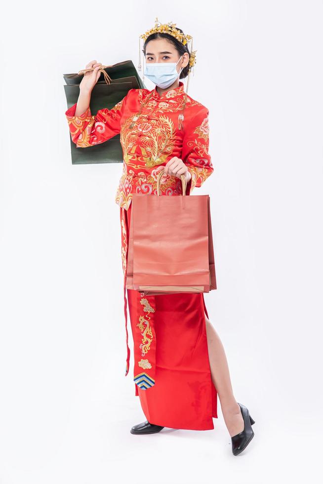 femme porter un costume cheongsam sourire avec un sac en papier du shopping dans le nouvel an chinois photo