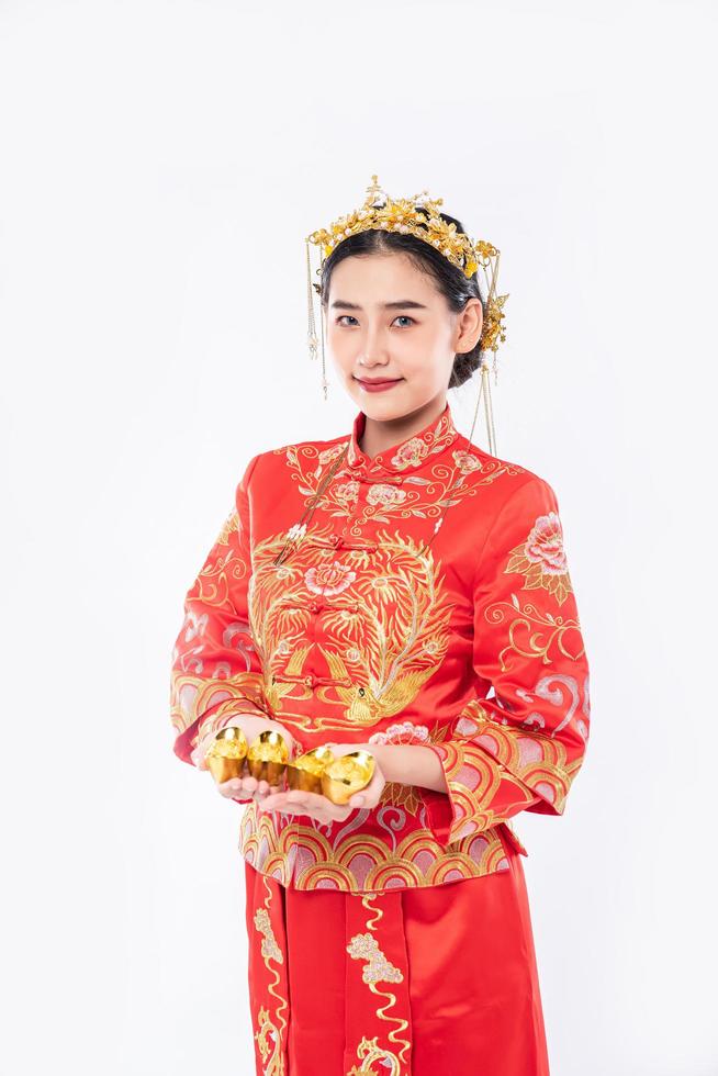une femme porte un costume cheongsam et une couronne donne de l'or à sa famille pour la chance du nouvel an chinois photo