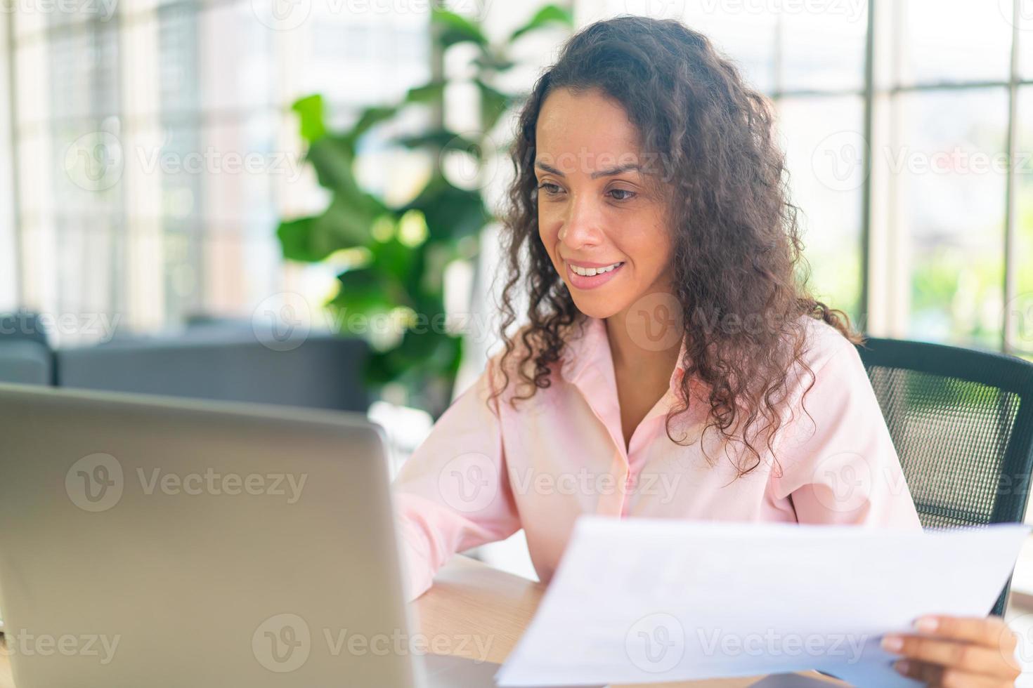 femme latine travaillant avec un ordinateur portable et du papier sur un espace de travail photo