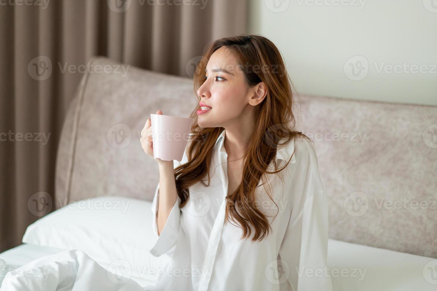 portrait belle femme se réveiller et tenant une tasse de café ou une tasse sur le lit photo