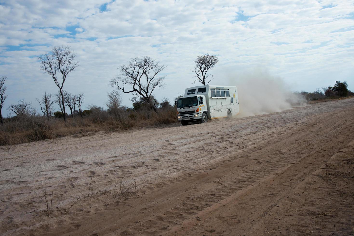 désert du kalahari, namibie, 2016, un camion pour touristes courant sur une route sablonneuse en namibie. poussière derrière la piste, plus de véhicules. namibie. photo