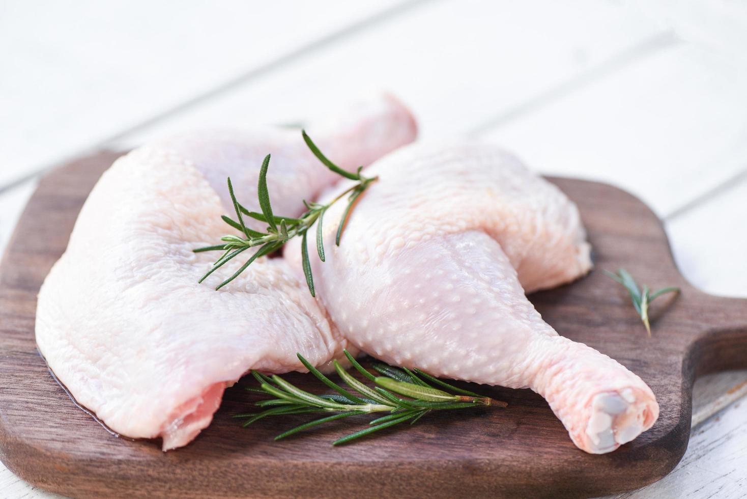 viande de poulet crue au romarin - filet de cuisse de poulet cru frais sur fond de planche à découper en bois photo