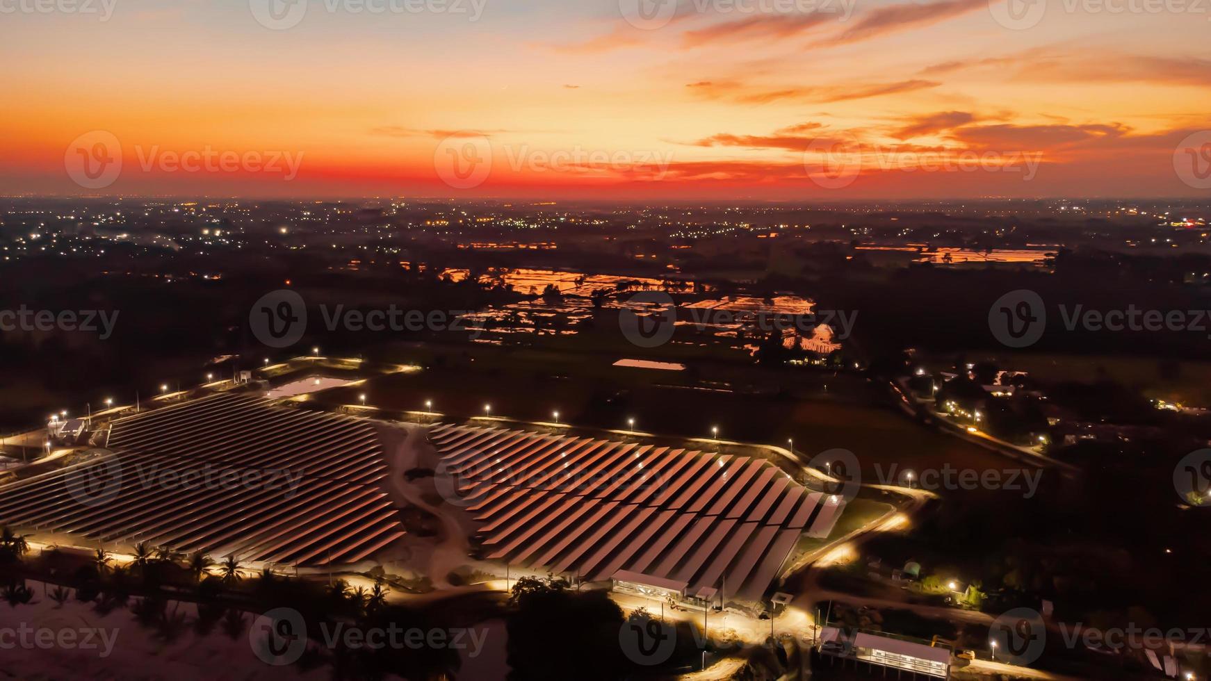 vue aérienne d'une ferme solaire produisant de l'énergie propre pendant la soirée au crépuscule. zone visible tout autour photo