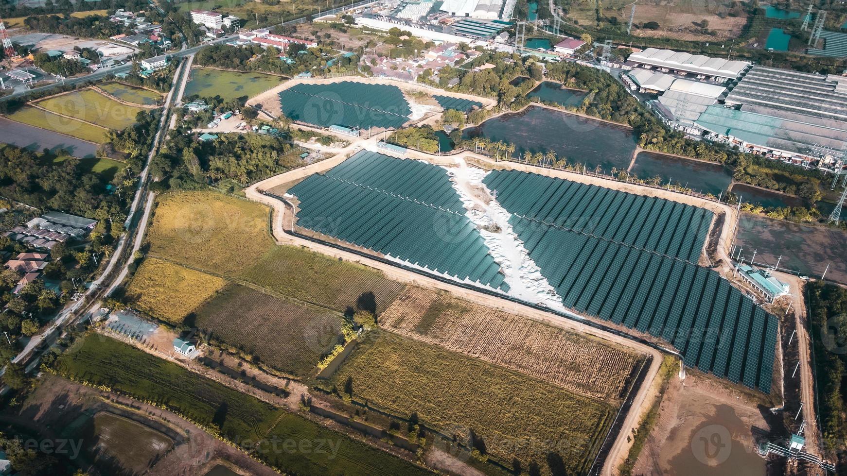 vue aérienne d'une ferme solaire produisant de l'énergie propre pendant la soirée. zone visible tout autour photo