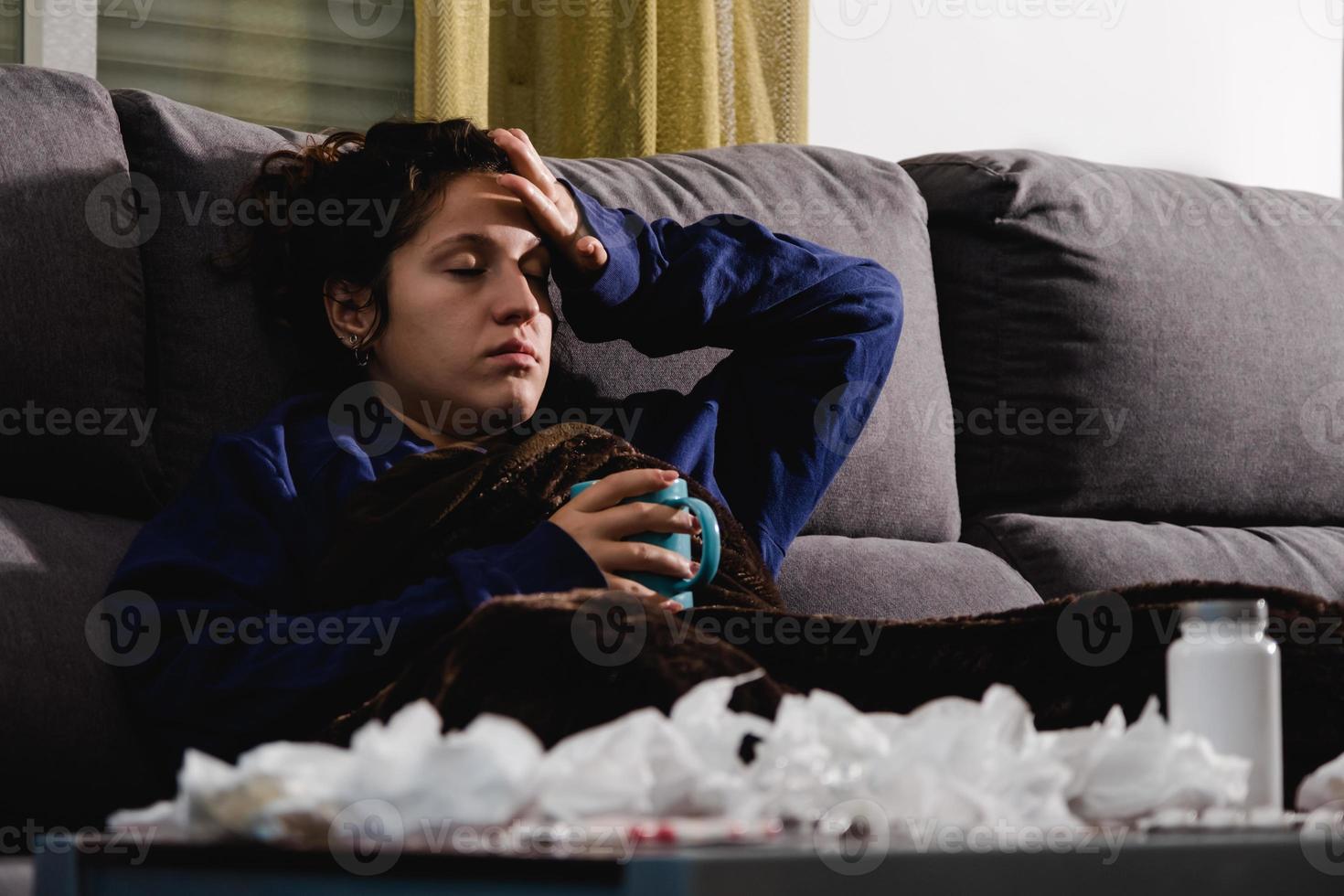 femme malade sur le canapé à la maison en train de boire une boisson chaude photo