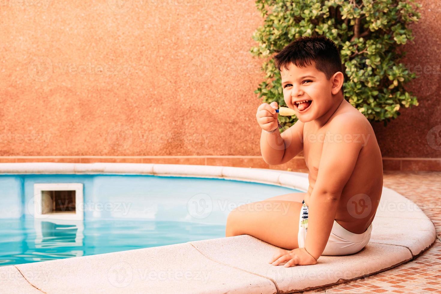 petit garçon heureux dans la piscine en mangeant une glace photo