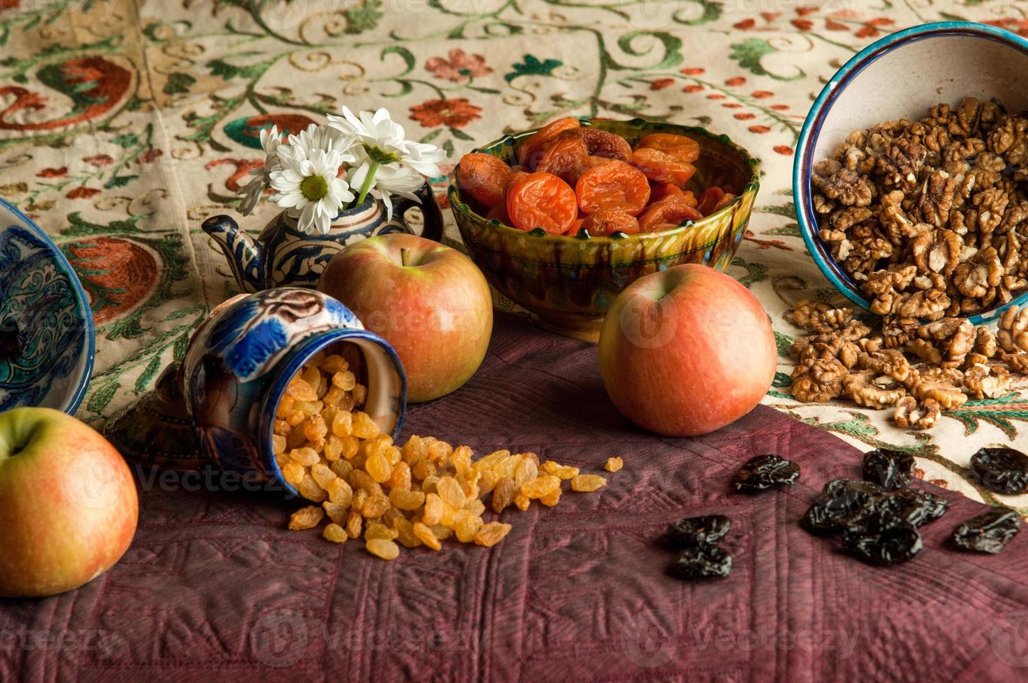 fruits secs dans des tasses sur une nappe ornementée orientale. nature morte de style oriental photo