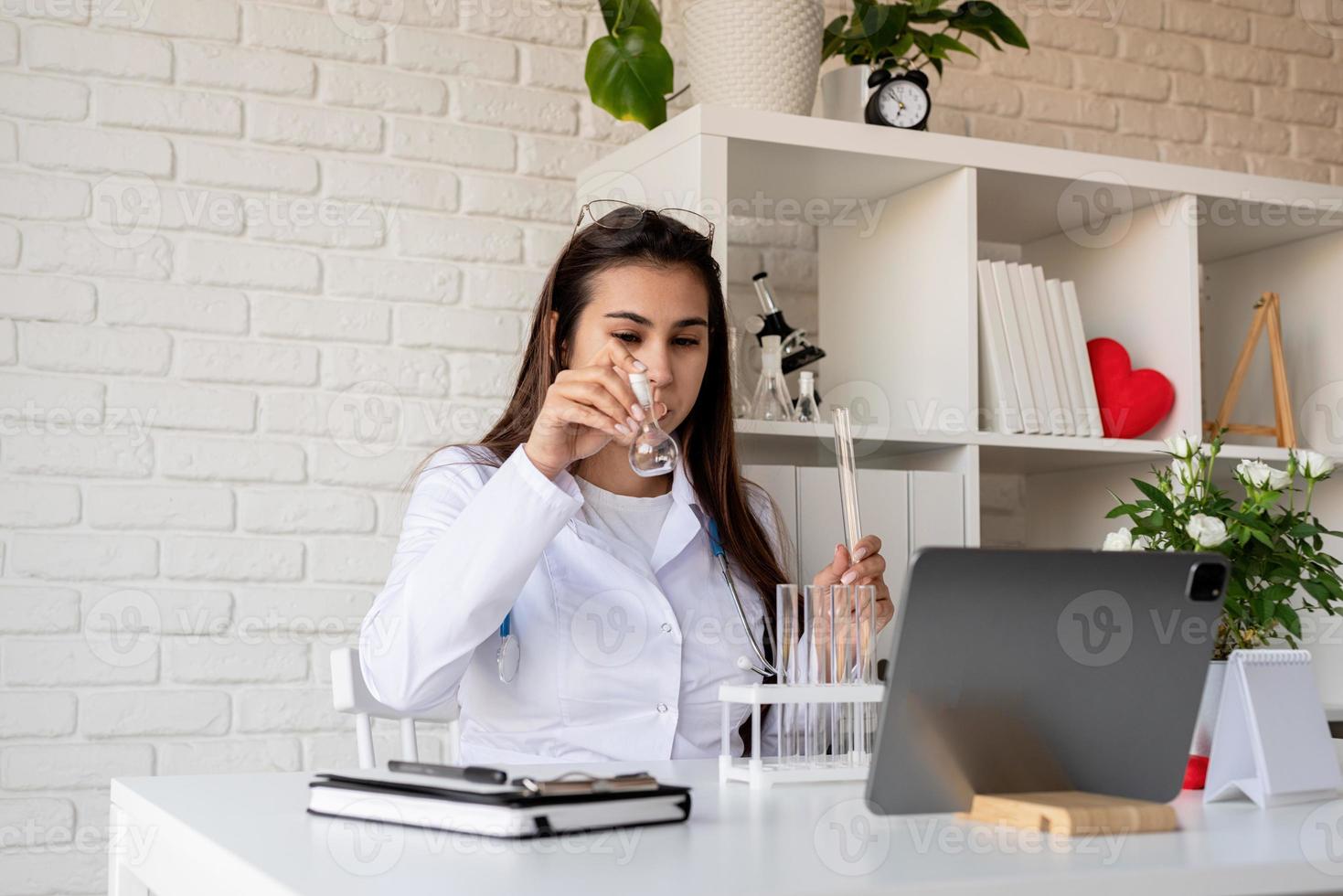 jeune femme médecin ayant un appel ou une consultation en ligne, médecin travaillant en ligne à domicile photo