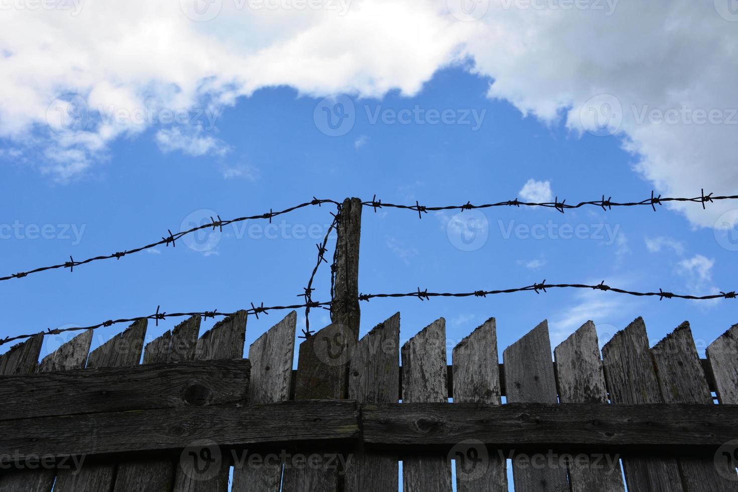 clôture avec du fil de fer barbelé. prudence, zone de danger. barrière interdite contre le ciel. photo