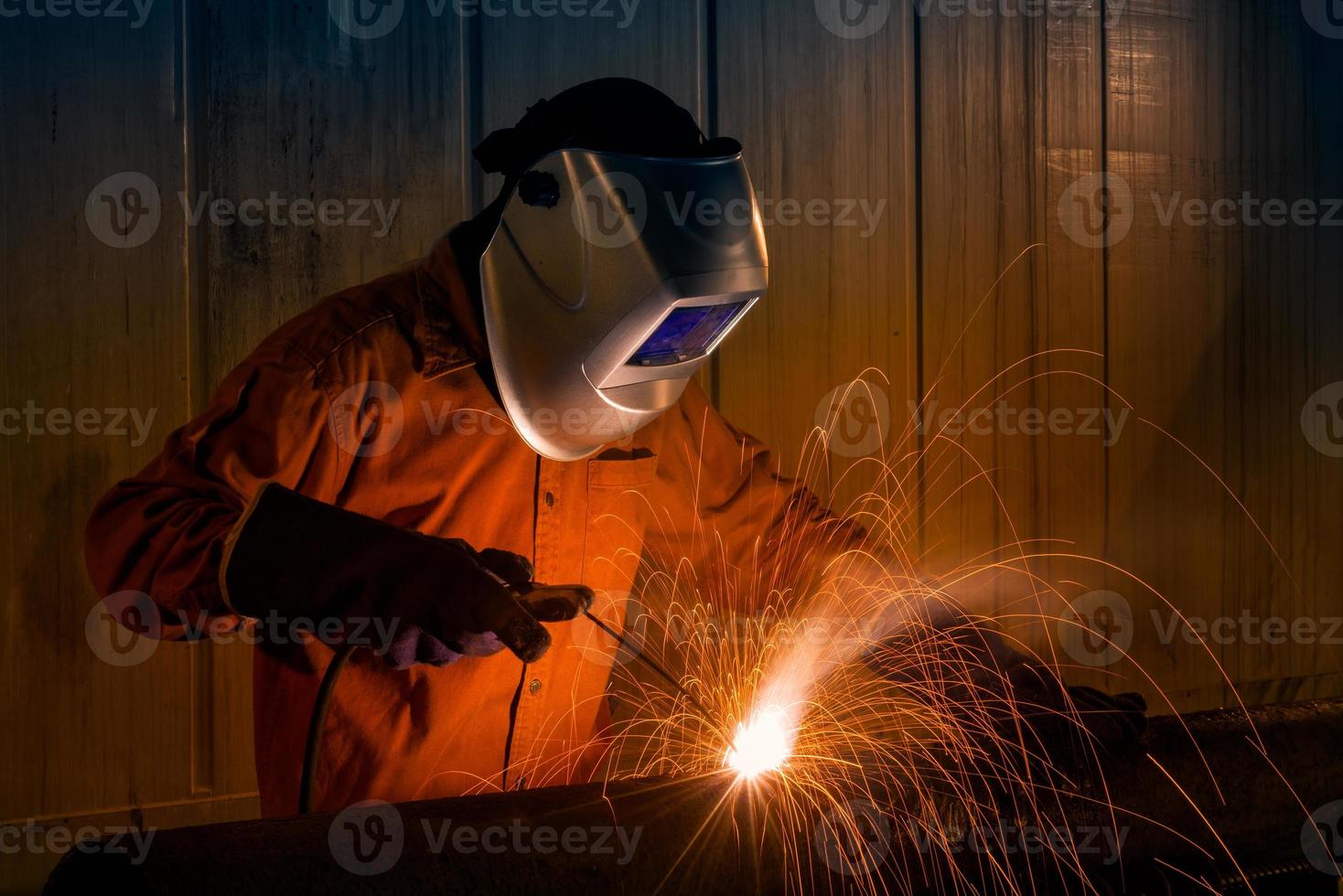 ouvrier industriel avec des équipements de sécurité et un masque de protection soudant une structure en acier dans une usine de construction. photo