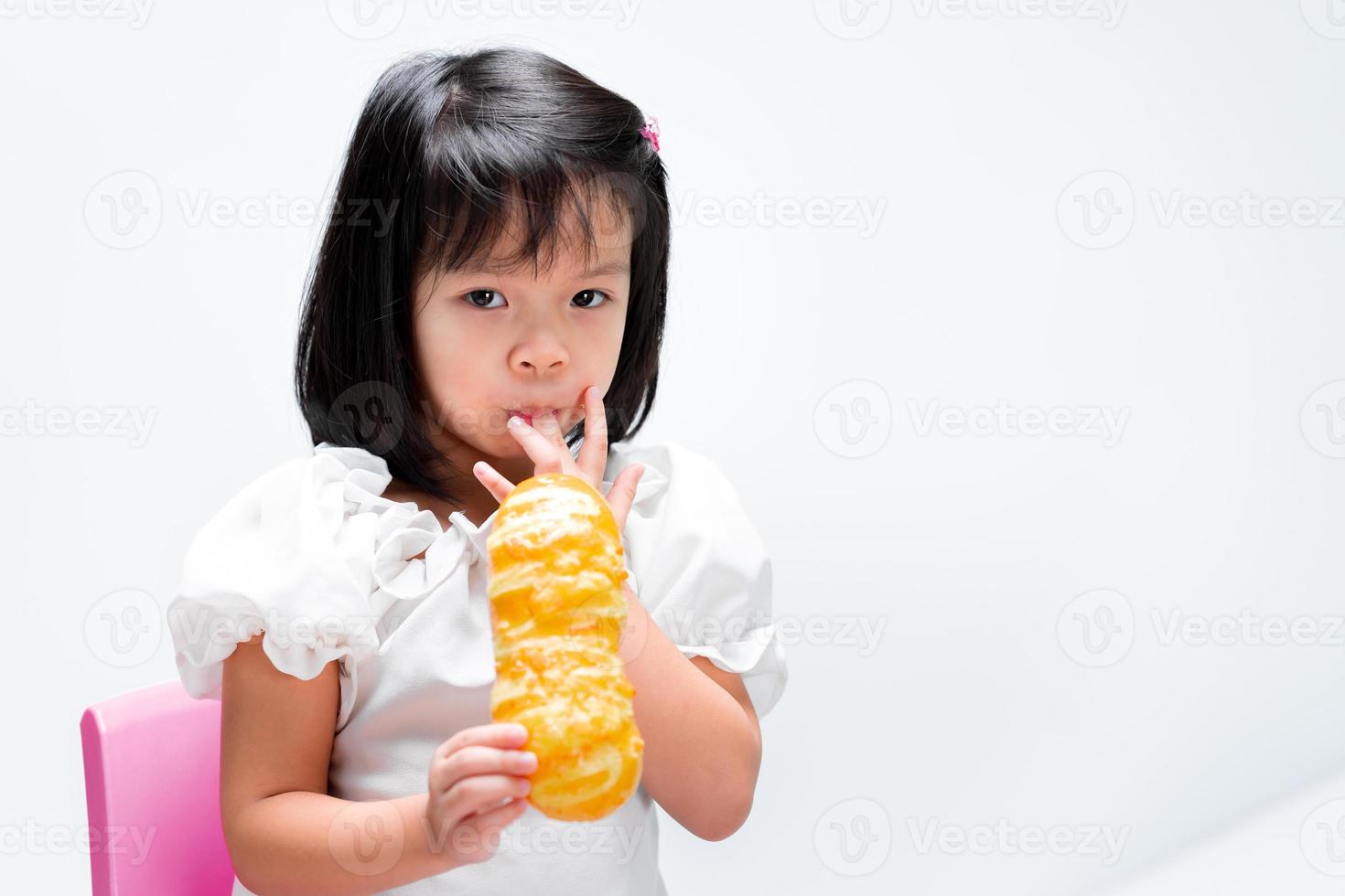 enfant s'amusant avec la boulangerie. les enfants sucent ses doigts tachés de confiture de pain. enfant portant un t-shirt blanc âgé de 4 ans. photo