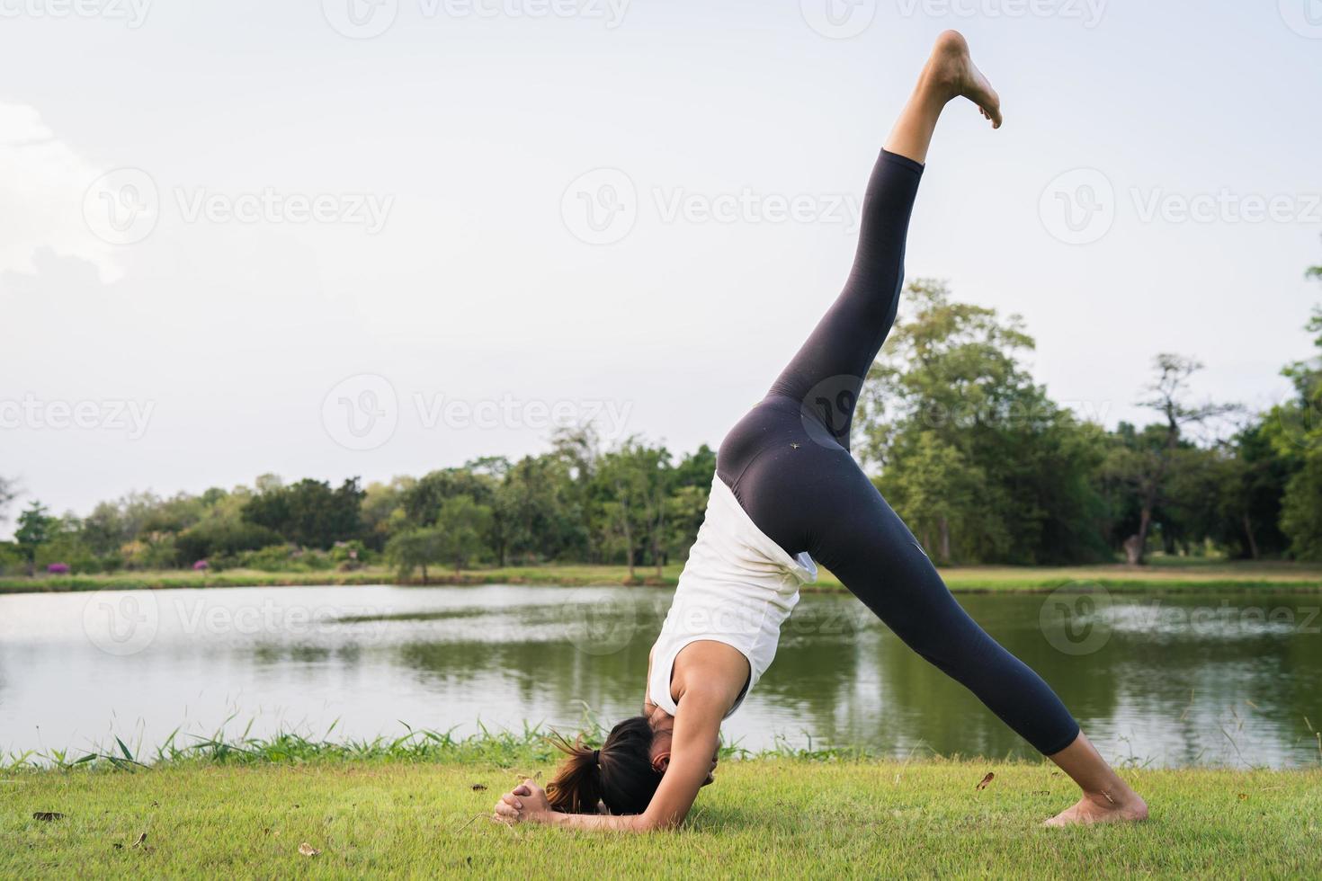 jeune femme asiatique yoga à l'extérieur reste calme et médite tout en pratiquant le yoga pour explorer la paix intérieure. le yoga a de bons avantages pour la santé près du lac du parc. concept de sport et de mode de vie sain. photo