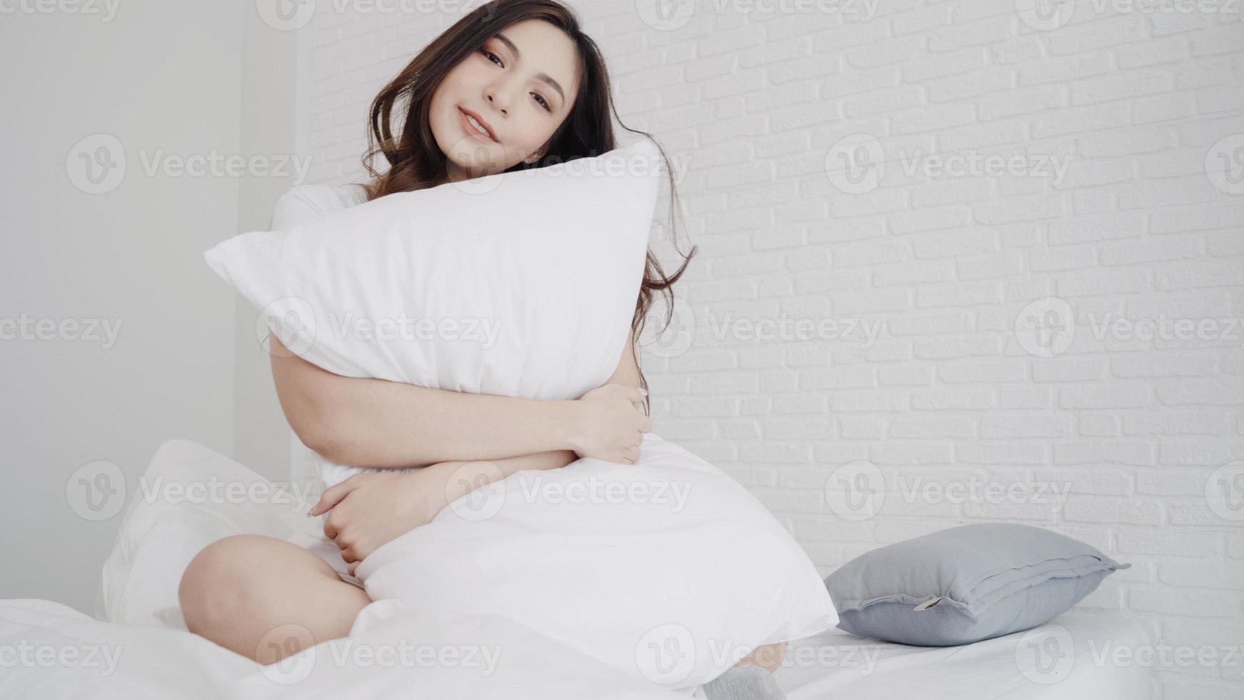 belle femme asiatique étirant son corps après s'être réveillée dans sa chambre à la maison. une femme heureuse profite d'une matinée ensoleillée. femme de style de vie à la maison concept. photo