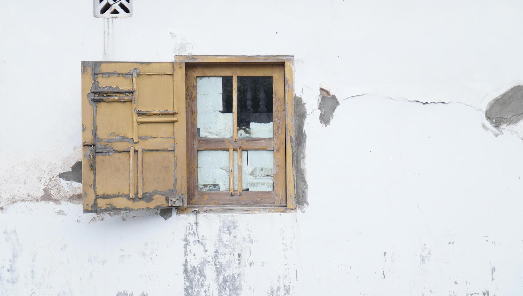 vieille fenêtre en bois sur un mur blanc endommagé photo