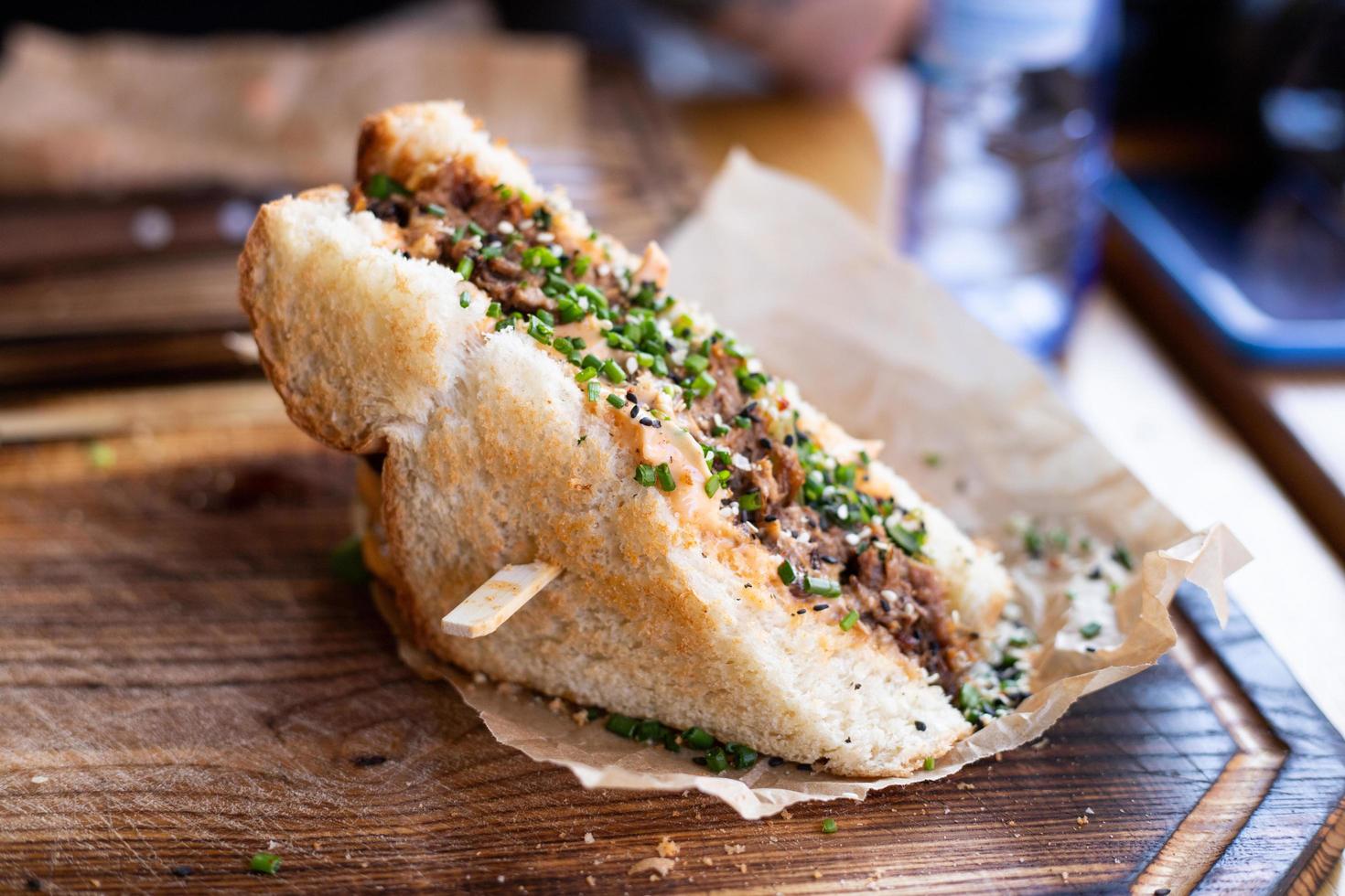 un sandwich croustillant avec de la viande et d'autres garnitures posé sur une table de restaurant. photo