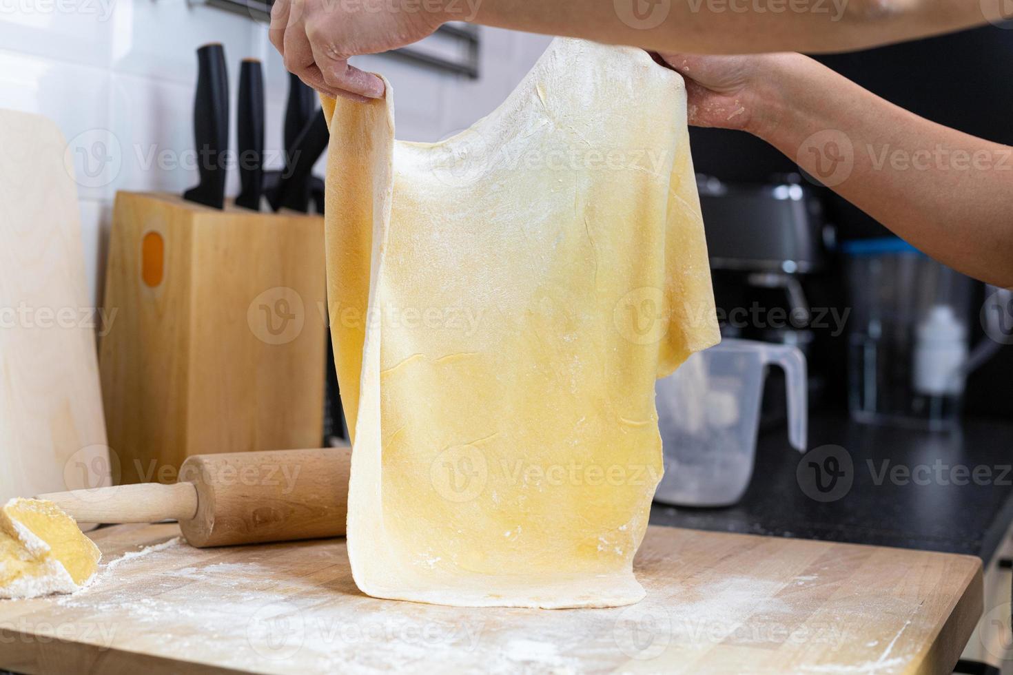 préparation de pâtes maison. une personne étirant un gros morceau de pâtes. photo