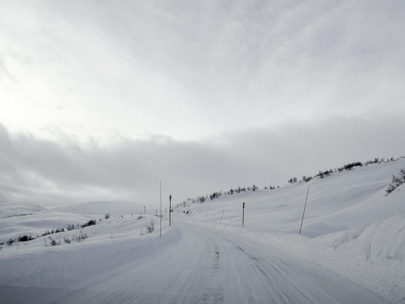 conduire à travers une route enneigée et un paysage en norvège. photo