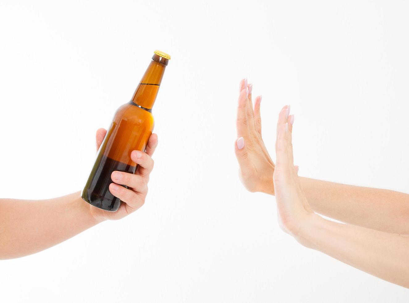 main féminine rejeter une bouteille de bière isolée sur fond blanc. concept anti-alcool. espace de copie photo